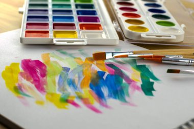 Renk örnekleriyle dolu beyaz bir çarşafta suluboya boyalar ve fırçalar. Yüksek kalite fotoğraf