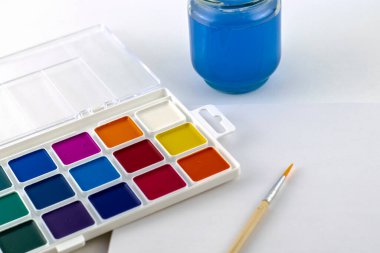 Suluboya, bir kavanoz su ve beyaz bir yüzeye çizim için bir çizim defteri çizmek için bir fırça boyar. Yüksek kalite fotoğraf