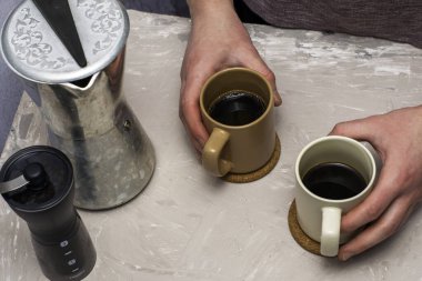 Kahve öğütücüsünün yanındaki adamın elinde iki kupa kahve ve masada bir gayzer. Yüksek kalite fotoğraf