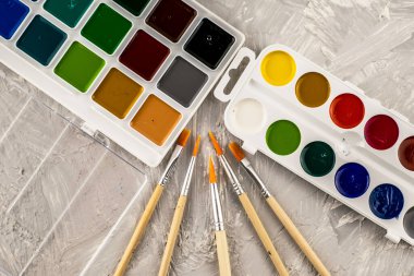 Gri desenli bir yüzeye çizim yapmak için suluboya boya ve fırçalar. Yüksek kalite fotoğraf