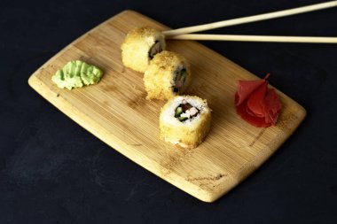Suşi ve tahtanın üzerinde wasabi çubukları ve zencefilli rulo. Yüksek kalite fotoğraf