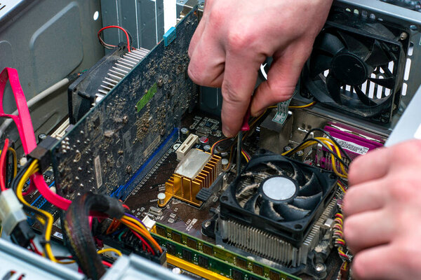 a master with a screwdriver in his hand repairs an old dusty computer. High quality photo