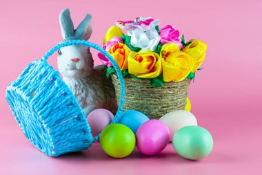 Çiçekli tavşan sepeti ve pembe arkaplan üzerinde paskalya yumurtaları olan ters çevrilmiş sepet. Yüksek kalite fotoğraf