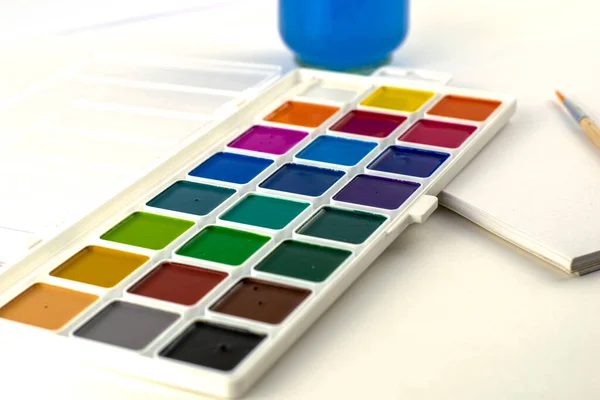 Υδατογραφία χρώματα βάζο βούρτσα με νερό και μπλοκ σκίτσο σε λευκό φόντο — Φωτογραφία Αρχείου