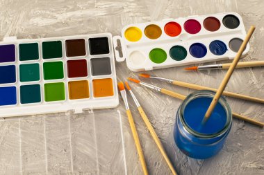 Suluboya, gri desenli bir yüzeye çizim yapmak için bir kavanoz su ve fırça boyar. Yüksek kalite fotoğraf