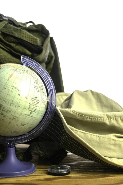 Рюкзак туристическая шляпа глобус и компас на белой стене фон туристической концепции — стоковое фото