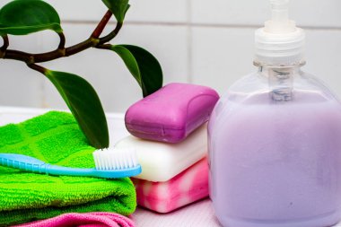 Bir yığın havlu sabun bir şişe sıvı sabun bir diş fırçası ve banyo masasında bir saksı.