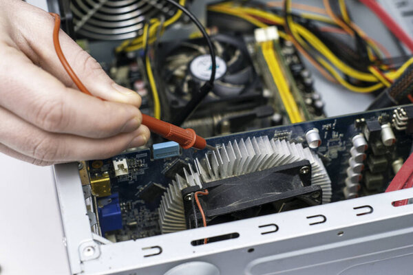 the master repairs the old computer checks the chips with a multimeter. High quality photo