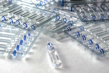 Beyaz zemin üzerinde cam ampulleri ve ayrı ampulleri olan şeffaf plastik kaplar. Yüksek kalite fotoğraf