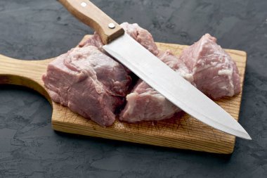 Kesme tahtasında parçalara ayrılmış bir et parçası ve yanında bir bıçak. Yüksek kalite fotoğraf