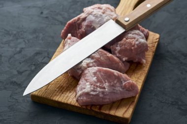 Kesme tahtasında parçalara ayrılmış bir et parçası ve yanında bir bıçak. Yüksek kalite fotoğraf