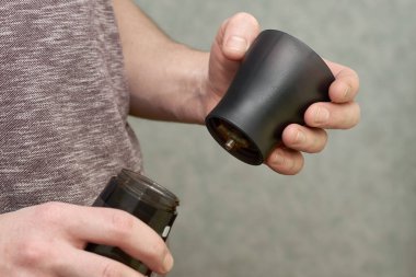 Kahve öğütücüsünde kahve öğüten bir adam kahve öğütücüsünden öğütülmüş kahve için vidaları söker.