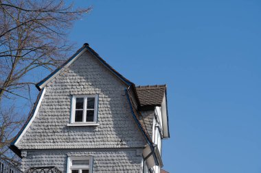 Ön cephesinde gri kiremitleri olan eski bir ev, mavi gökyüzü ve kopyalama alanı