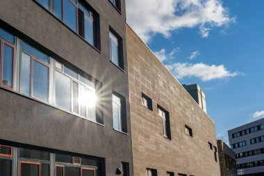 Penceresinde güneş ışınları olan modern bir binanın cephesi.