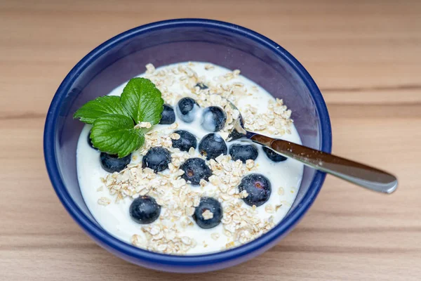Muesli with oatmeal and blueberries in a blue bowl