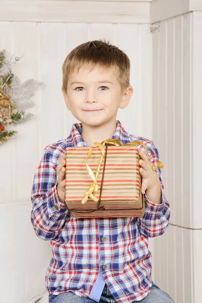 Mignon garçon tenant cadeau de Noël étonné avec sourire pour surprise. — Photo