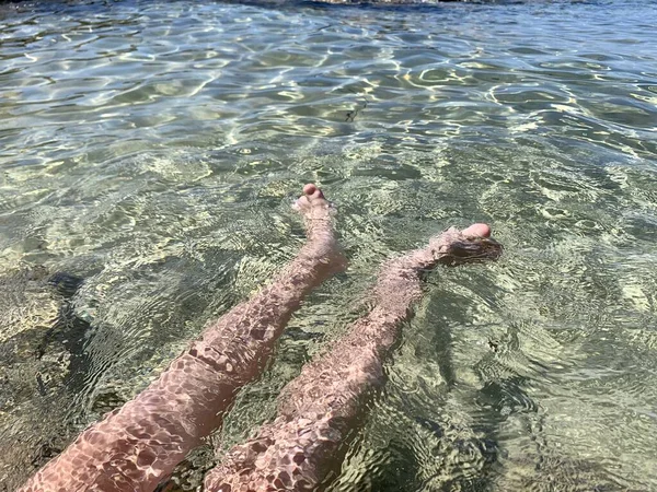 10代の男の子が砂浜に座って夏の日を楽しんでいます 男の子の裸の足 海での休暇 — ストック写真