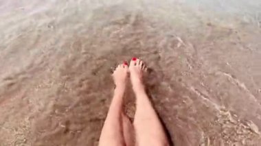 Denizde kumsalda kadın ayakları