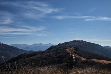 Kafkasyalı genç erkek gezgin büyük bir sırt çantasıyla dağlarda yürüyor ve doğa manzarasının tadını çıkarıyor. İyi hava ve turistler yedekte ünlü patikada yürürler..