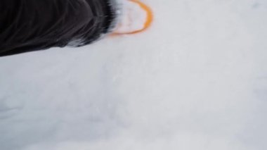Ayak manzaralı karları tekmeliyor. 4K görüntüler yavaş çekim. Karlı kış havası, temiz havada yürümek. Soğuk bir günde tüylü kar, sarı lastik çizmelerle yürüyor..