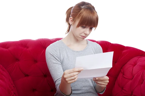 Young beautiful red haired girl get bad news on red sofa in fron — Stock Photo, Image