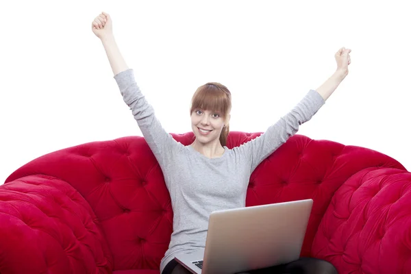 Young beautiful red haired girl on red sofa raise arms in the ai — Stock Photo, Image