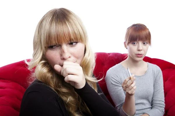 Young beautiful blond and red haired girls on red sofa in front — Stock Photo, Image