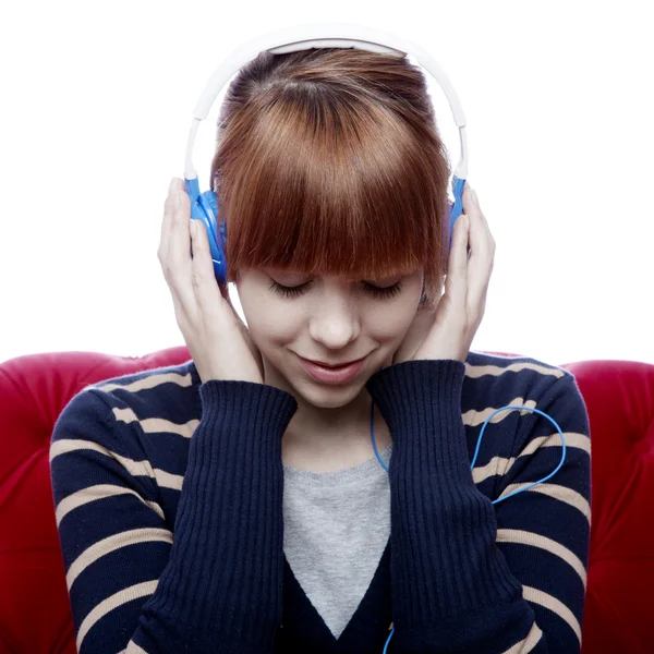 Young beautiful red haired girl on red sofa listen to great musi — Stock Photo, Image