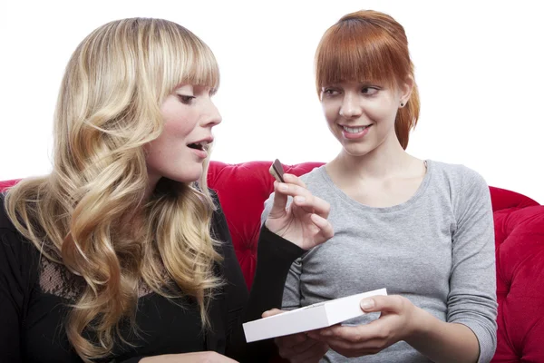 Young beautiful blond and red haired girls eating chocolate on r — Stock Photo, Image