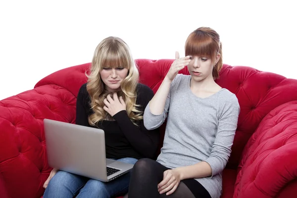 Young beautiful blond and red haired girls on red sofa in front — Stock Photo, Image