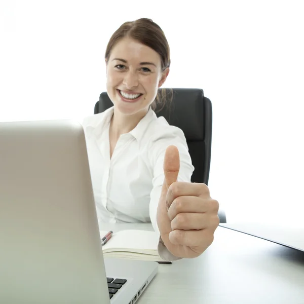 Young brunette business woman thumb up desk — Stock Photo, Image