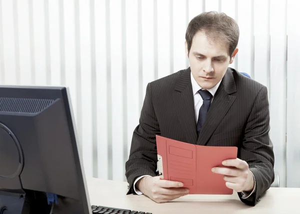 Besorgter Geschäftsmann liest ein Dokument auf seinem Schreibtisch — Stockfoto