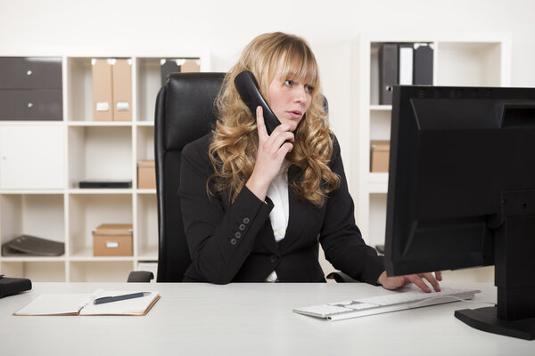 Деловая женщина разговаривает по телефону во время печатания
