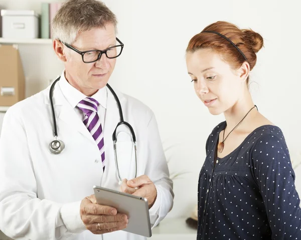 Lekarza i pacjenta kobieta poszukuje czegoś na komputerze typu tablet — Zdjęcie stockowe