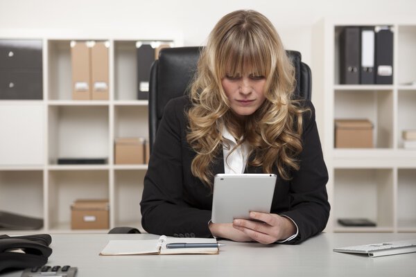 Женщина, читающая сообщение на планшете на работе
