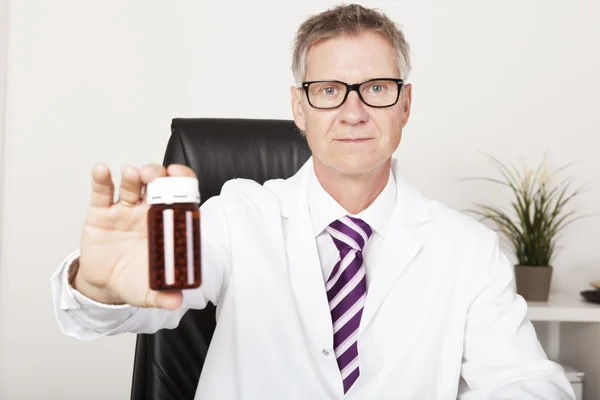 Pharmacist holding out a bottle of pills — Stock Photo, Image
