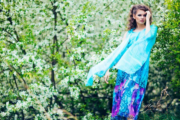 Mulher bonita em vestido azul entre árvores de maçã flor, moda — Fotografia de Stock