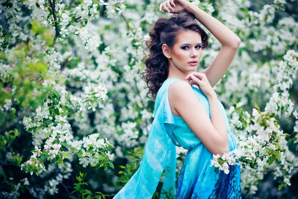 Belle femme en robe bleue parmi les pommiers en fleurs, mode — Photo