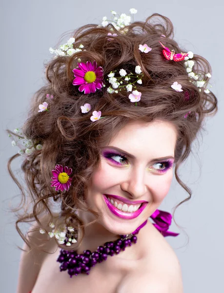 Jovem feliz com flores em seu cabelo e maquiagem brilhante — Fotografia de Stock