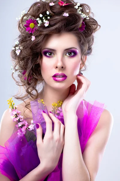 Mujer hermosa joven con flores en el pelo y maquillaje brillante —  Fotos de Stock