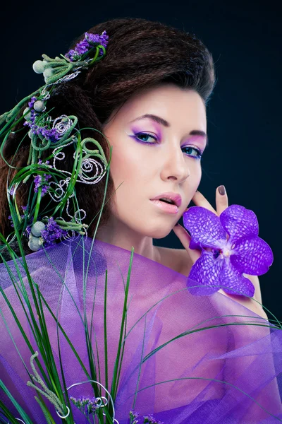 Schönheit Mädchen mit Orchideenblüten und professionellem Make-up — Stockfoto