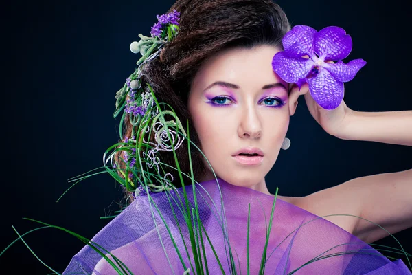 Menina de beleza com flores de orquídea e maquiagem profissional — Fotografia de Stock