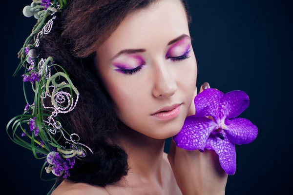 Skönhet flicka med orkidé blommor och professionell makeup — Stockfoto