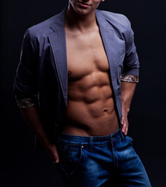 szexi macsó fiatalember nyitott kabát alatt sötét háttér