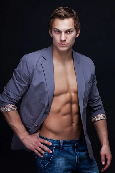 Young sexy macho man with open jacket over dark background — Stock Photo, Image