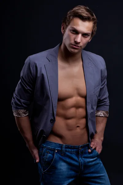 Jonge sexy macho man met open jas over donkere achtergrond — Stockfoto