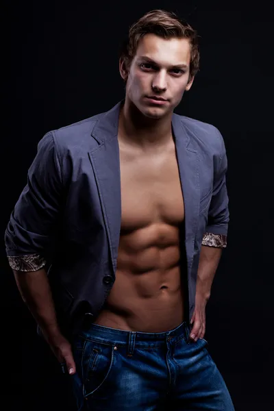 Young sexy macho man with open jacket over dark background — Stock Photo, Image