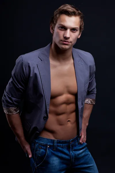 Young sexy macho man with open jacket over dark background — Stock Photo, Image