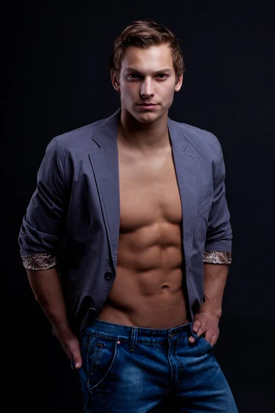 Young sexy macho man with open jacket over dark background — Stock Photo, Image