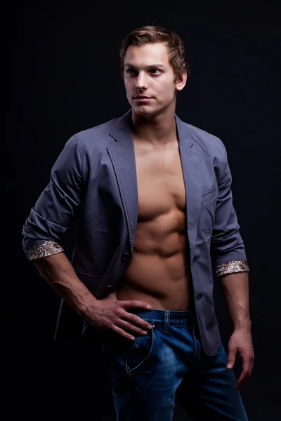 Jonge sexy macho man met open jas over donkere achtergrond — Stockfoto